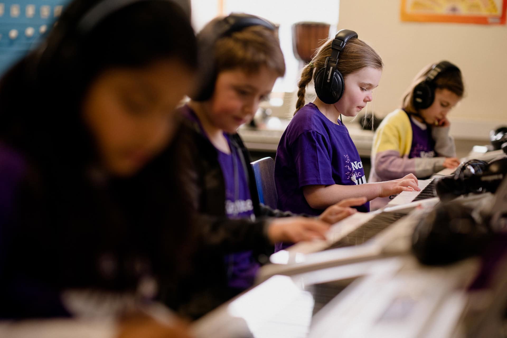 Ältere Kinder spielen im KeyNotes-Unterricht nebeneinander auf Keyboards.
